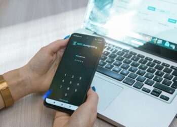 a person holding a cell phone in front of a laptop