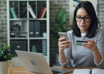 a woman sitting at a table looking at her cell phone